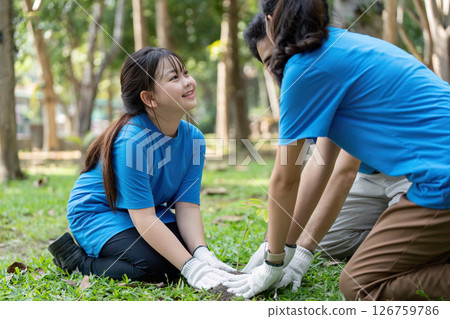 Family volunteers planting trees together in a green park for a better environment 126759786