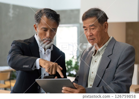 Elderly professionals using a tablet for business insights Elderly professionals using a tablet for business insights 126759858