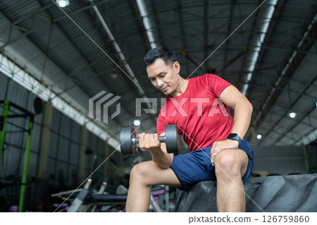 Wellness and Strength Training. Man lifting dumbbell in gym for fitness. Wellness and Strength Training. Man lifting dumbbell in gym for fitness. 126759860