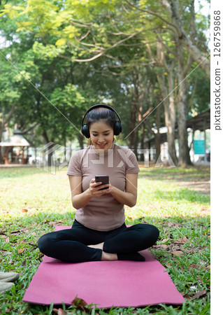 Wellness and Connection. Young woman enjoying music on her phone while practicing mindfulness outdoors. Wellness and Connection. Young woman enjoying music on her phone while practicing mindfulness outdoors. 126759868