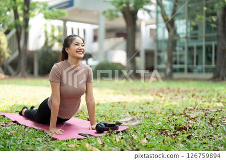 Wellness and Fitness. Young woman practicing yoga pose on mat outdoors for relaxation and joy. Wellness and Fitness. Young woman practicing yoga pose on mat outdoors for relaxation and joy. 126759894