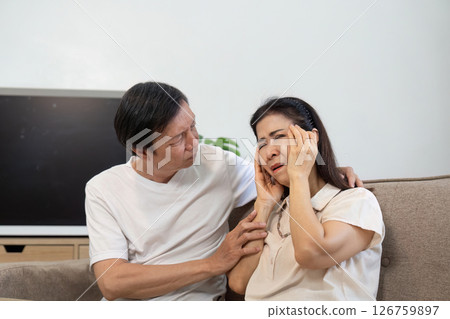 Elderly couple sharing a moment of concern. A man comforts a distressed woman in their living room. Elderly couple sharing a moment of concern. A man comforts a distressed woman in their living room. 126759897
