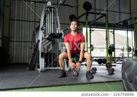 Wellness and Strength. Man performing kettlebell swing for full body workout at gym. Wellness and Strength. Man performing kettlebell swing for full body workout at gym. 126759898