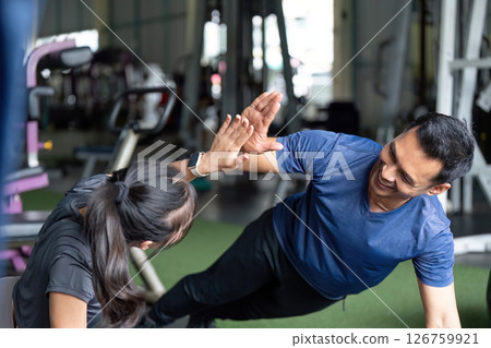 Wellness and Friendship. Friends engaging in playful fitness challenge at the gym. Wellness and Friendship. Friends engaging in playful fitness challenge at the gym. 126759921