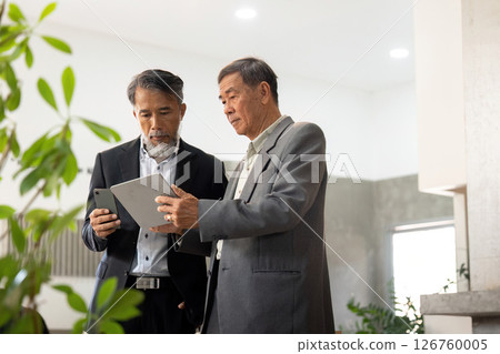 Elderly men collaborating on a digital device Elderly men collaborating on a digital device 126760005
