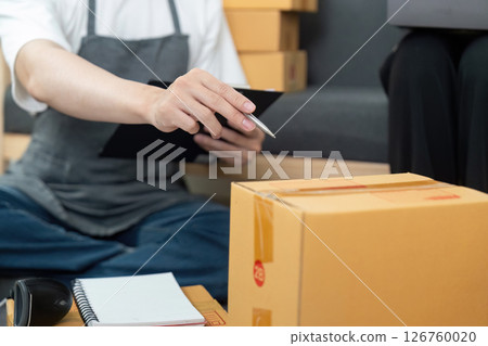 Couple reviewing inventory details in a modern workspace. Couple reviewing inventory details in a modern workspace. 126760020
