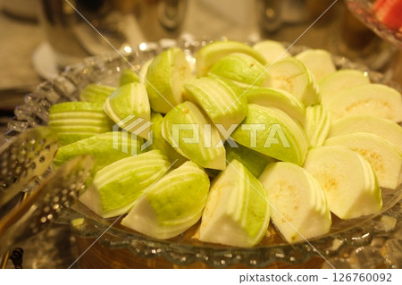 A close up shot of guava salad served with Indian mixed spices green salt on a white plate. 126760092