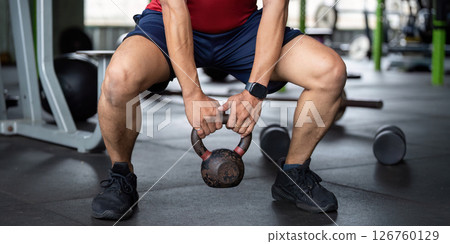 Wellness in Action. Man squatting with kettlebell in gym. Wellness in Action. Man squatting with kettlebell in gym. 126760129