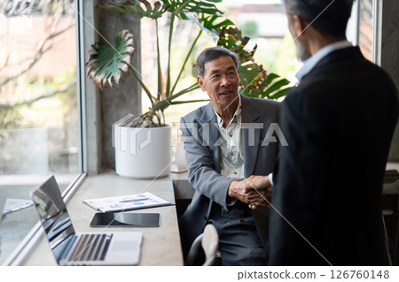 Elderly man shaking hands with business partner in office 126760148