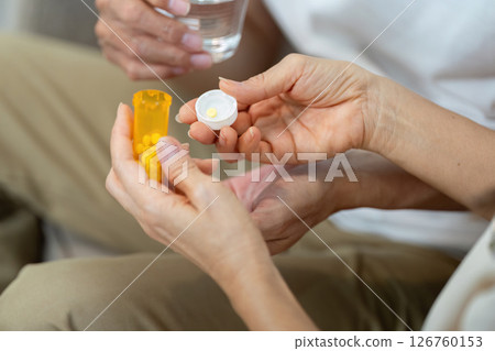 Wellness and Medication Management. Elderly couple sharing medication routine at home. 126760153