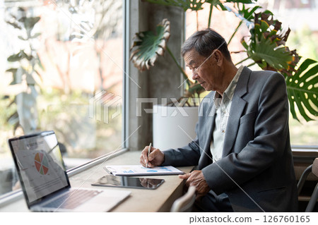 Elderly man analyzing data on tablet in modern workspace Elderly man analyzing data on tablet in modern workspace 126760165