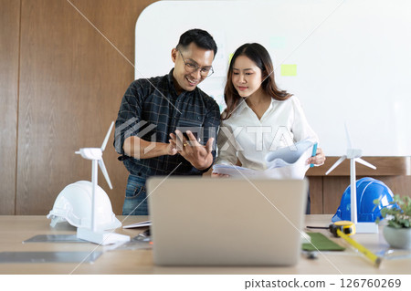 Sustainability and Engineering. Engineers discussing eco-friendly designs with a smartphone. Sustainability and Engineering. Engineers discussing eco-friendly designs with a smartphone. 126760269