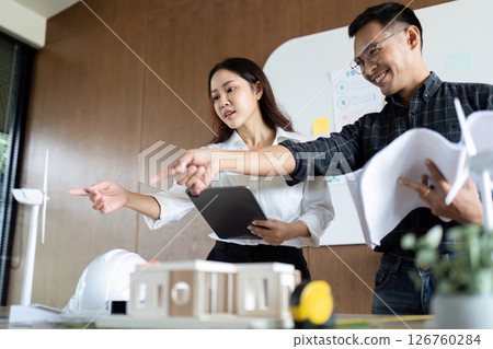 Sustainability and Engineering. Engineers pointing out features of eco-friendly designs in a collaborative setting. 126760284