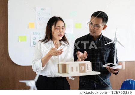 Sustainability and Engineering. Engineers presenting eco-friendly models in a collaborative workspace. 126760389