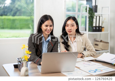 Team Collaboration and Data Analysis. Businesswomen engaging with laptop and reports. Team Collaboration and Data Analysis. Businesswomen engaging with laptop and reports. 126760420