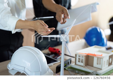 Sustainability and Engineering. Engineers reviewing a wind turbine model during a project meeting. 126760456