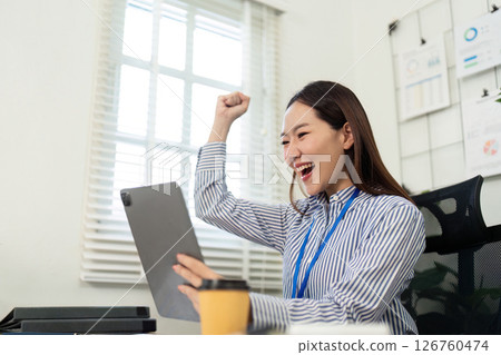 Celebrating Success. Happy businesswoman cheering at tablet in office. 126760474
