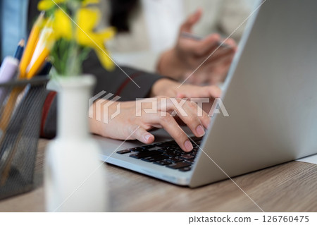 Collaboration and Productivity. Business professionals discussing project details with laptop and flowers. 126760475