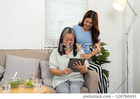 Wellness and Technology. Mother and daughter sharing a joyful moment while using a tablet. 126760491