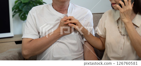 Elderly couple addressing health issues. A woman speaks on the phone while comforting her distressed partner. 126760581