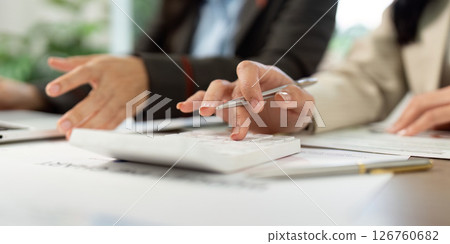 Calculating Success. Close-up of hands using a calculator and discussing financial data. 126760682