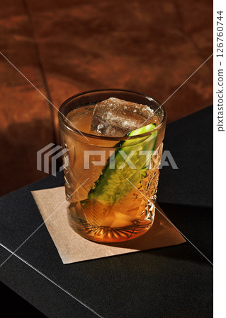 Refreshing cocktail with cucumber and ice in elegant glass on bar counter 126760744
