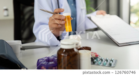 Doctor Holding Prescription Bottle and Reviewing Medication 126760746