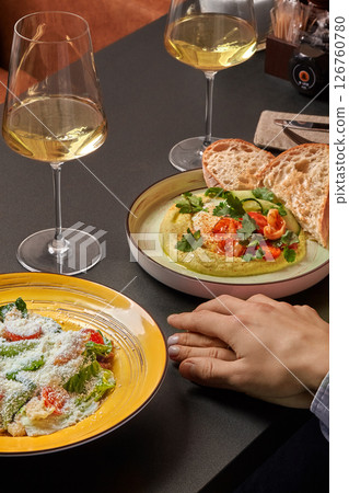 Couple enjoying dinner with wine, caesar salad, and hummus at restaurant 126760780