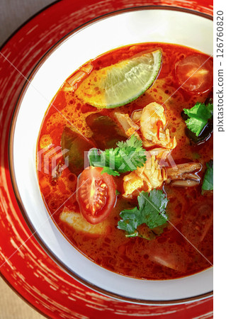 Spicy tom yum soup with shrimp, lime, and cilantro in a bowl 126760820