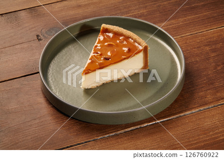 Slice of delicious caramel cheesecake resting on a green plate on a wooden table Slice of delicious caramel cheesecake resting on a green plate on a wooden table 126760922