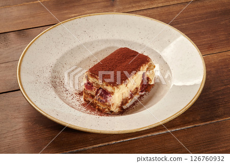 Delicious tiramisu cake with cocoa powder on elegant plate: indulging in sweet treat Delicious tiramisu cake with cocoa powder on elegant plate: indulging in sweet treat 126760932