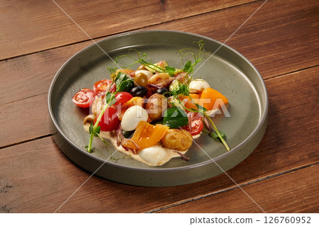 Delicious mediterranean salad with potatoes, cherry tomatoes, cucumber, olives, eggs, and orange pepper on rustic wooden table 126760952