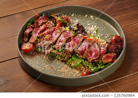 Sliced beef salad with parmesan and cherry tomatoes on wooden table 126760964