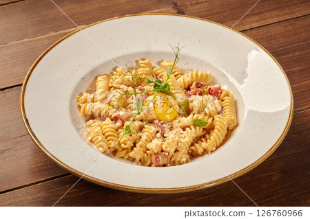 Delicious pasta carbonara with egg yolk and parmesan cheese on wooden table Delicious pasta carbonara with egg yolk and parmesan cheese on wooden table 126760966