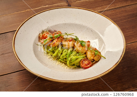 Delicious green fettuccine pasta with grilled shrimps and pesto sauce on white plate 126760968