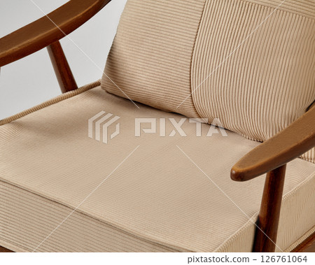 Comfortable modern armchair with wooden frame and beige upholstery invites relaxation 126761064