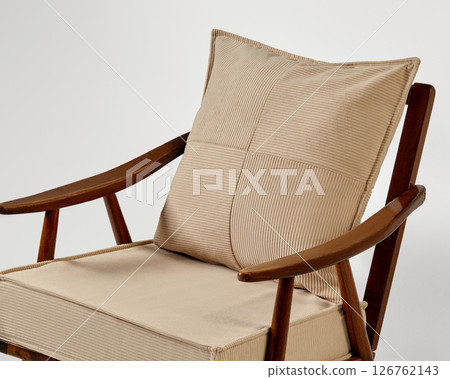 Comfortable beige upholstered armchair with wooden frame and matching cushion Comfortable beige upholstered armchair with wooden frame and matching cushion 126762143
