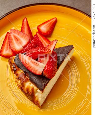Basque burnt cheesecake with fresh strawberries on yellow plate 126762205
