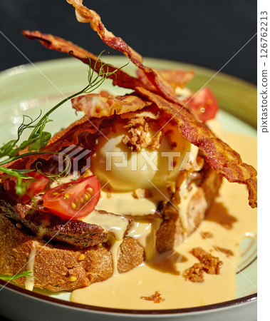 Gourmet breakfast or brunch with eggs benedict, bacon, hollandaise sauce, and cherry tomatoes on toasted bread 126762213