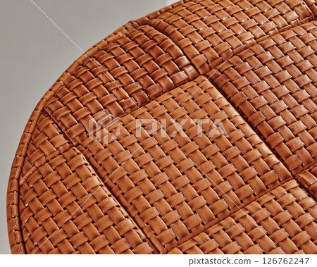 Close-up of woven leather upholstery creating textured surface on round furniture 126762247