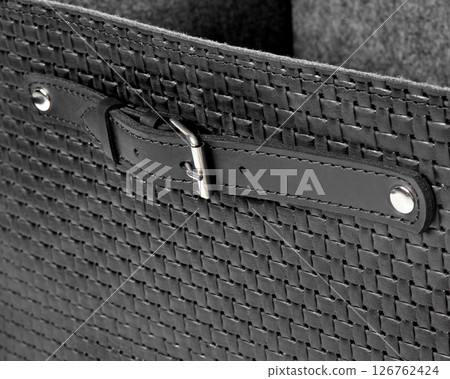Black leather basket with strap and buckle showing weaving detail 126762424