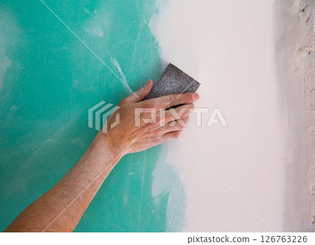 plastering man hand sanding the plaste in drywall seam plastering man hand sanding the plaste in drywall seam 126763226