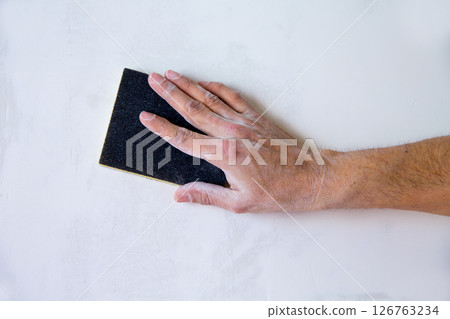 plastering man hand sanding the plaster plastering man hand sanding the plaster 126763234