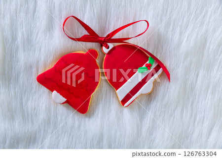 Christmas cookies red bell shape and ribbon on white fur Christmas cookies red bell shape and ribbon on white fur 126763304