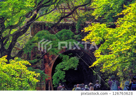 People walking through an abandoned tunnel with fresh greenery 126763628