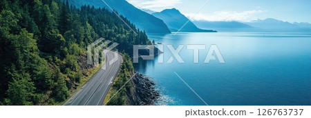 Coastal highway winding through forested cliffs above calm ocean waters 126763737