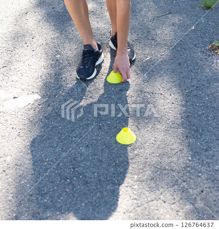 Athlete placing training cones on asphalt.  Preparation for drills or a workout. 126764637
