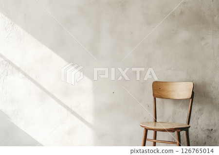 Wooden chair by textured wall in sun 126765014