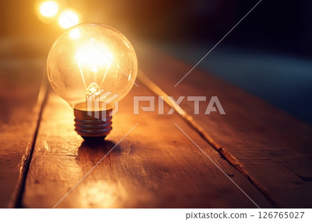 Light bulbs illuminate wooden table at night 126765027