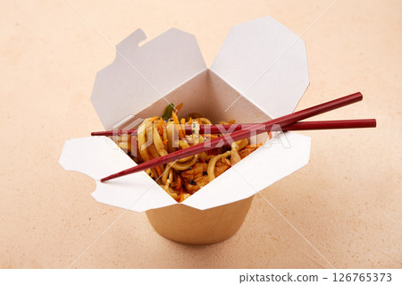 Noodles served in takeout box with chopsticks on a simple background 126765373